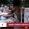 Indian security personnel carrying a detained protester beside a student placard during the July 2026 NEET demonstrations